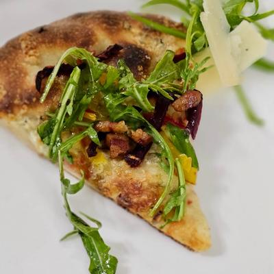 A slice of a gourmet pizza from Rossana's Table.