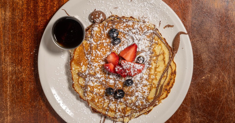 Pancakes with Nutella and berries, powdered sugar and maple syrup