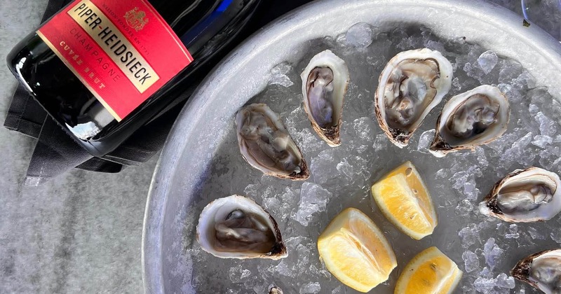 Bottle of champagne served alongside raw oysters on ice