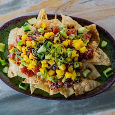 Tuna poke nachos with mango salsa, scallions, and sesame seeds.