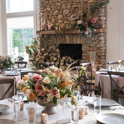 Wedding reception featuring tables with floral arrangements and a rustic stone fireplace