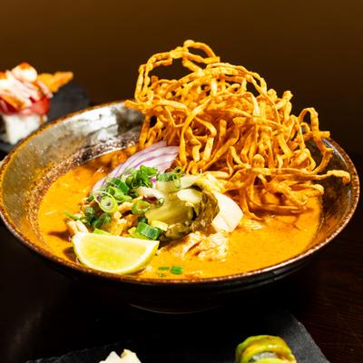 Coconut curry soup topped with crispy noodles and herbs.