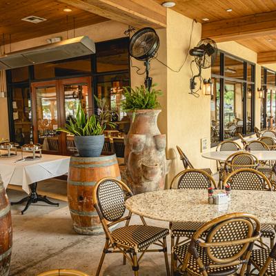 Covered patio with tables, chairs, and potted plants.