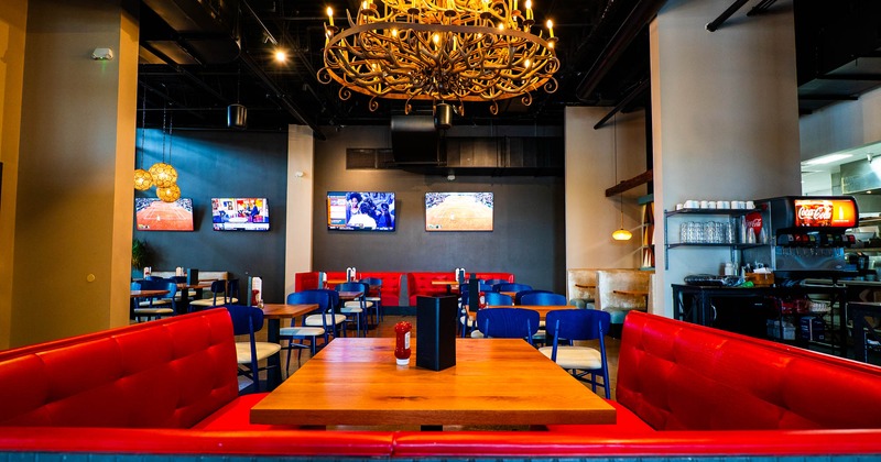 Interior, dining area, seating booth, tables for four and two in the back, TVs on the wall