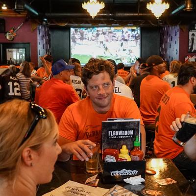 Guys in orange jerseys and a big tv in the back