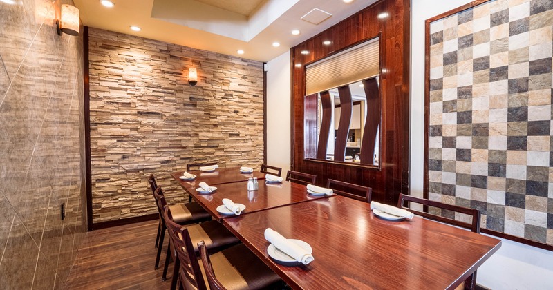 Dining room with a large wooden table set for eight, featuring a stone wall, a mirror