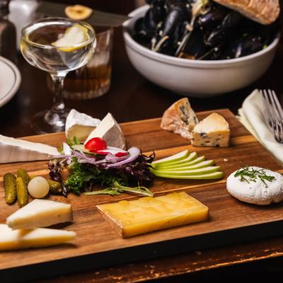 Plate of cold meats and cheeses displayed with food and drinks.