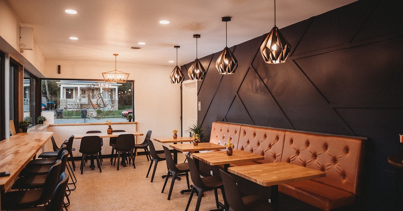 Interior, seating area, long leather padded banquette bench with tables and chairs, table for six