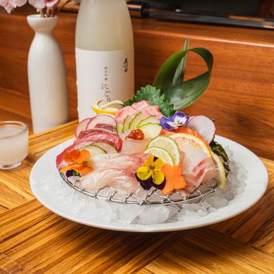 Sashimi platter served over ice, alongside bottle of sake.