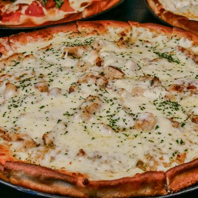 Chicken Alfredo pizza with melted cheese and herbs.