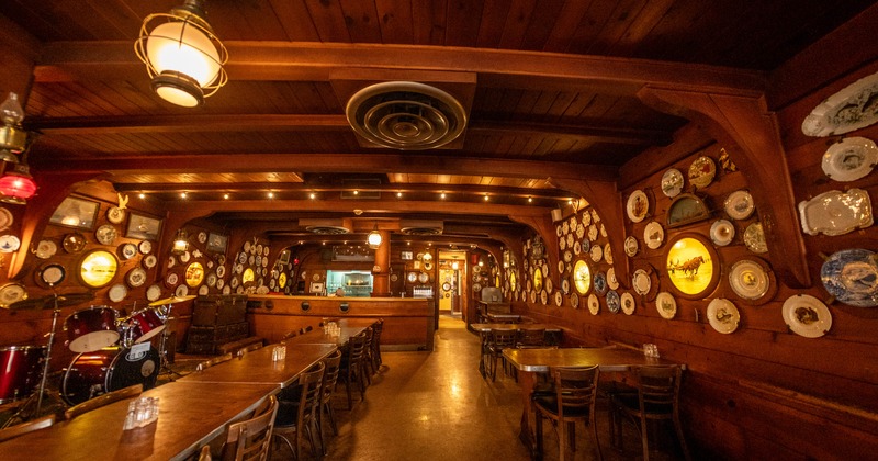 Interior seating area with wooden walls covered in decorative plates and a long dining table