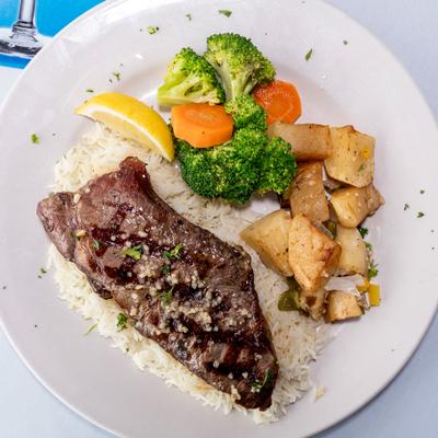 New York strip steak served over rice with roasted potatoes and steamed vegetables.