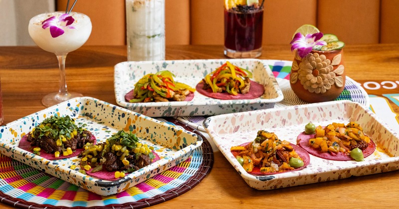 Trays of assorted tacos and cocktails on a table