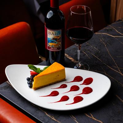 Cheesecake slice with berries and fruit garnish on a white plate.