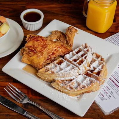 Chicken and waffles, fresh fruit cup,  maple syrup, and orange juice.