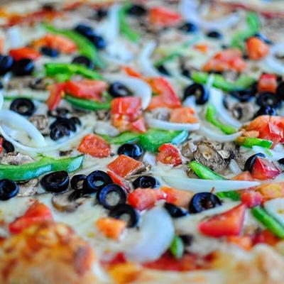 Close-up of a vegetable pizza with onions, olives, and peppers.
