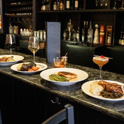 several entrees and drinks lined up on the bar.