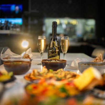 Various dishes served on the table with bottle and two glasses of sparkling wine.