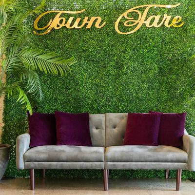 A gray sofa with purple cushions set against a green wall featuring the Town Fare sign.
