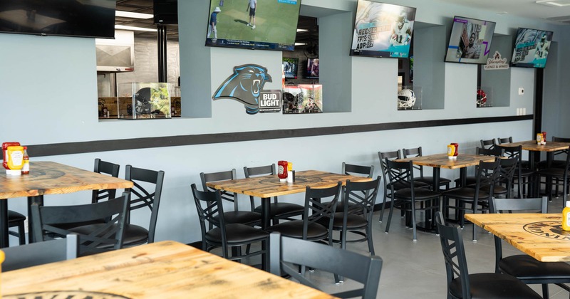 Interior, seating area, tables for six, TV sets hanging on the wall, condiments on the tables