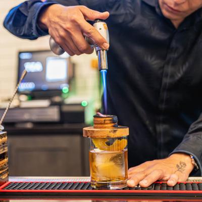 A bartender preparing a smoked cocktail.  Nicoya Old Fashioned with Flor de Cana rum.