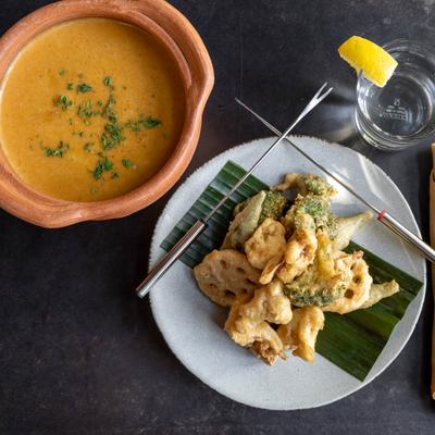 Fried Tofu & Mixed Veggies Satay Fondue with a clay pot with sauce, and a glass of water.