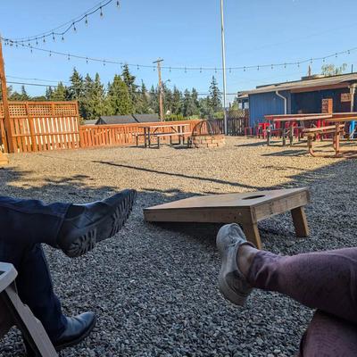 Rustic outdoor patio with gravel ground and cornhole boards.