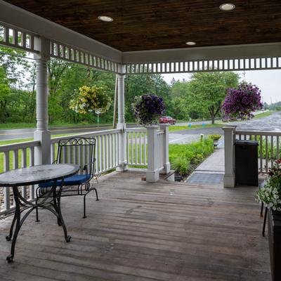 Covered porch on a rainy day, with hanging flower baskets and a metal table set.