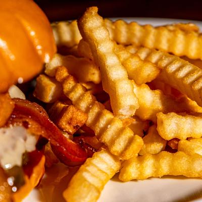 Burger served with crinkle cut fries, close-up.