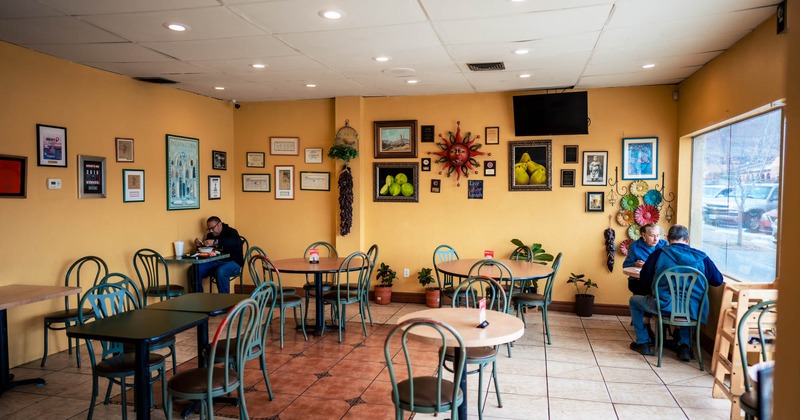 Room with tables and chairs, yellow walls with lots of framed pictures