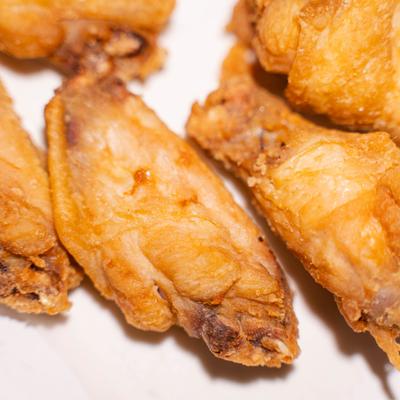 Golden crispy fried chicken wings on a white plate.