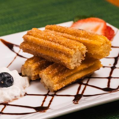 Plate of Churros served with whipped cream and berries.