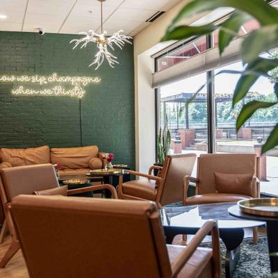 Interior featuring brown leather armchairs arranged around a table and neon signage.