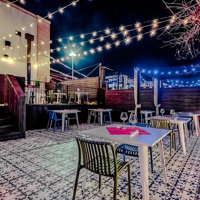 A nighttime patio scene with tables and chairs.