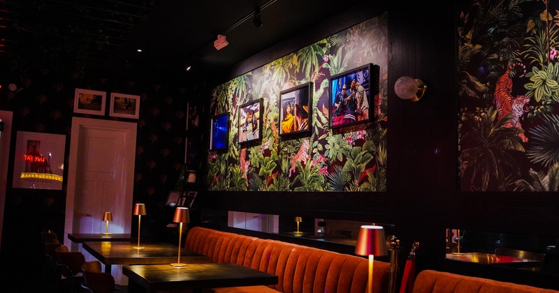 Cozy seating area, walls decorated with vibrant tropical wallpaper and framed photographs