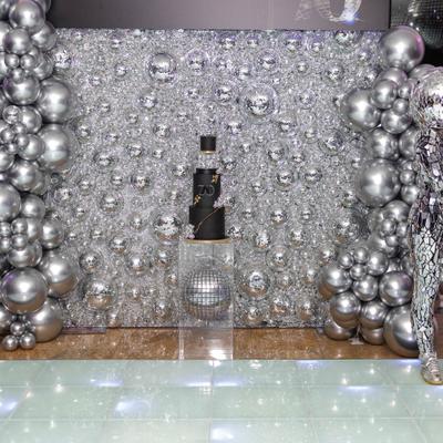 Silver sequin backdrop framed by metallic balloon clusters.