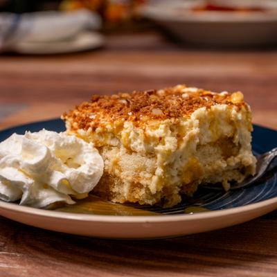 Slice of apple crumble cake with whipped cream on a plate.