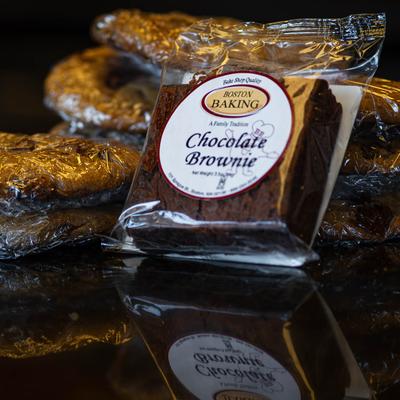 A packaged chocolate brownie with other pastry in the background.