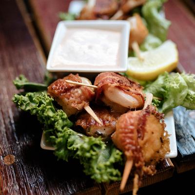 Skewer and dipping sauce on a lettuce leaf, close up.