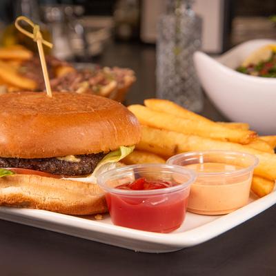Beef burger served with fries and dipping sauces.