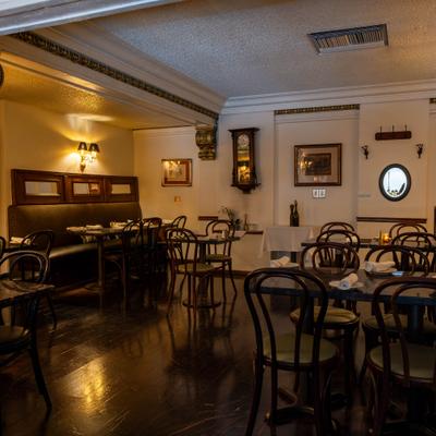 Dimly lit restaurant interior featuring dark wood furniture and booths.