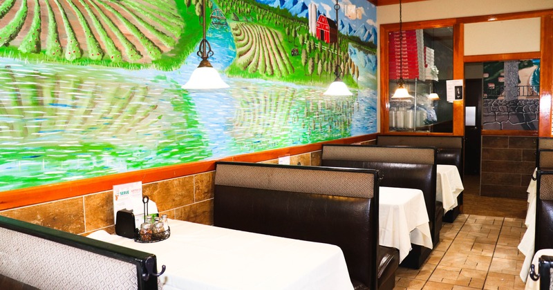 Restaurant interior with booths and a large mural of a rural landscape