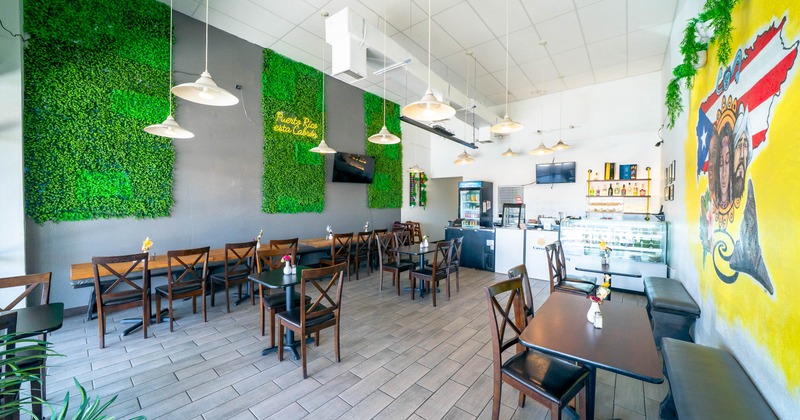 Interior of a modern restaurant with green plant wall, tables, and chairs