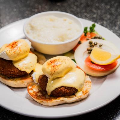 Crab cake eggs Benedict with hollandaise sauce and a side of grits.