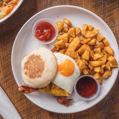 Breakfast burger with bacon, and a fried egg, served with home fries