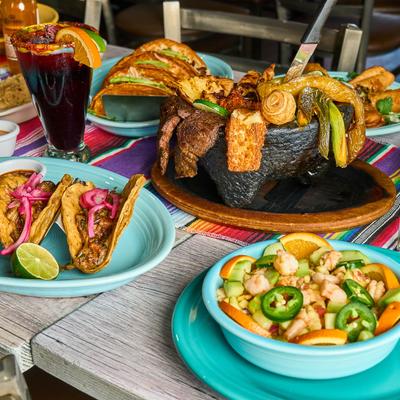 A vibrant table spread featuring tacos, ceviche, mixed molcajete, and sangria.