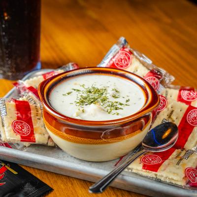 A bowl of New England Clam Chowder served with packed crackers.