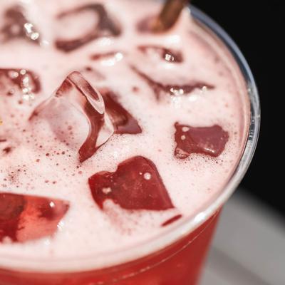 Red cocktail served in a plastic cup, close-up.