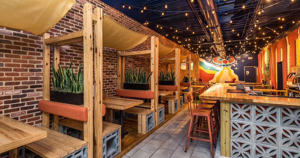 Interior, seating booths with tables, bar with bar stools on the right, lanterns on the ceiling