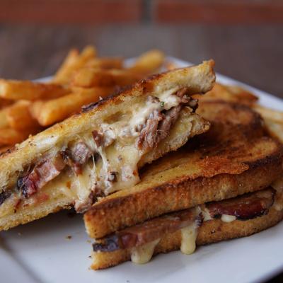 Brisket grilled cheese sandwich with a side of fries.